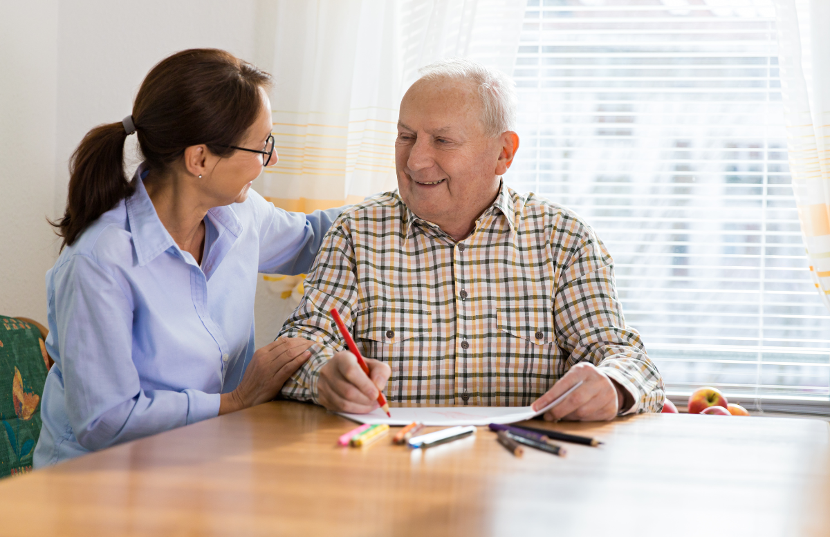 occupational-therapist-helping-an-elderly-man-write-with-a-red-pencil