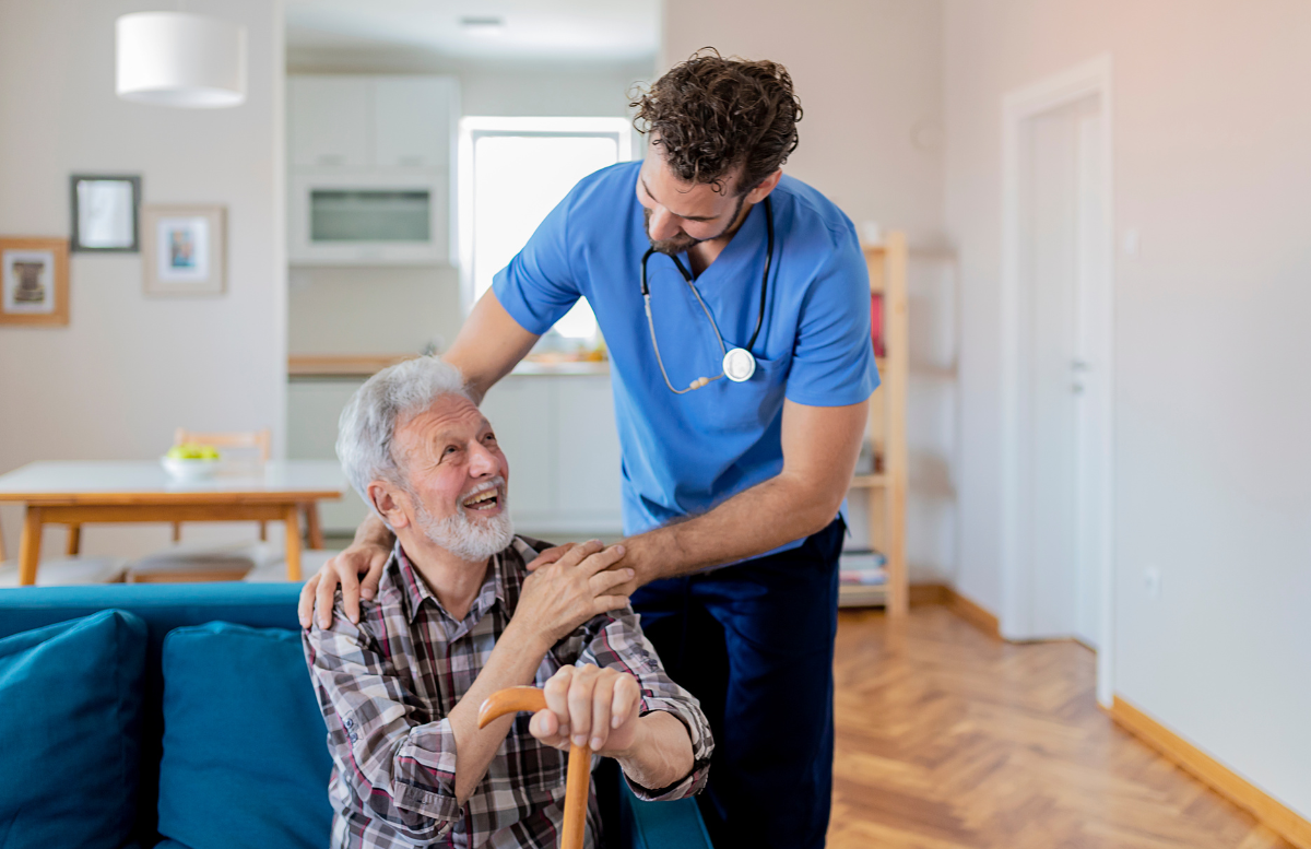 male-caregiver-with-his-hands-on-the-shoulders-of-an-elderly-man-who-is-holding-a-walking-cane